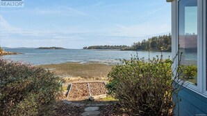 Una propiedad costera con vista al mar, una terraza de madera y una casa con un gran ventanal.