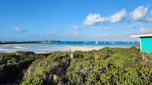 A coastal view with a beach, boats, and a turquoise building.