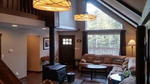 A cozy living room with a large window, a fireplace, and a comfortable sofa.