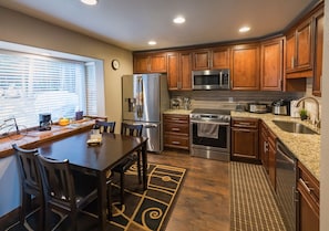 Enjoy cooking in this well-equipped kitchen with a large island, refrigerator, microwave, oven, and sink.