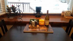 A wooden table with a coaster holding a bottle of wine, a salt shaker, a pepper shaker, and a can of beer.
