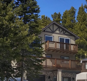 Classic two-story home with a spacious balcony and lush surroundings.