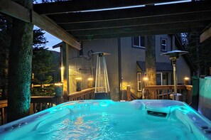 A hot tub area with a wooden deck, a ladder leading to a deck, and a house in the background. - Colorado Mountain Retreat - Spacious Cabin with Hot tub (Idaho Springs)