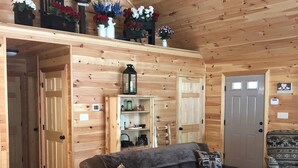 Interior acogedor de una cabaña con techo de madera, un sofá, una mesa de centro y un banco.