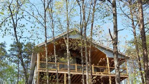 Una cabaña con fachada de madera, varios balcones y rodeada de árboles.