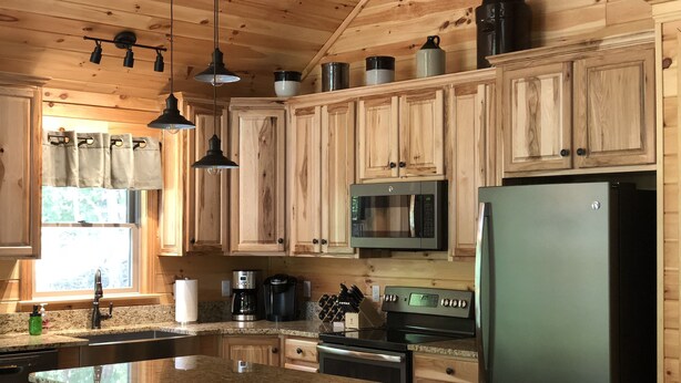 Una cocina con armarios de madera, encimera de granito, microondas, refrigerador y cafetera.