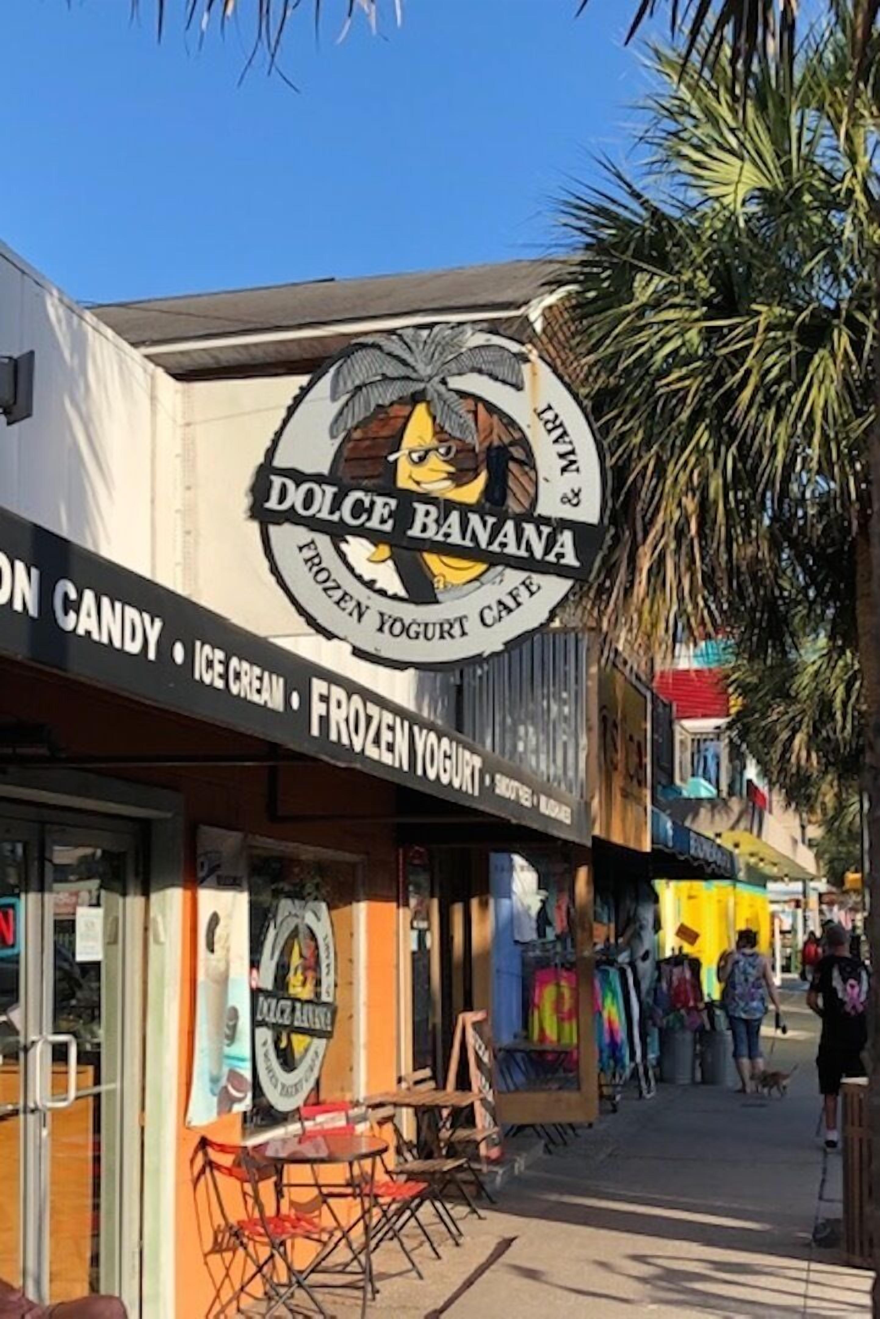 A storefront with a sign for 'Dolce Banana' offering frozen yogurt and ice cream.