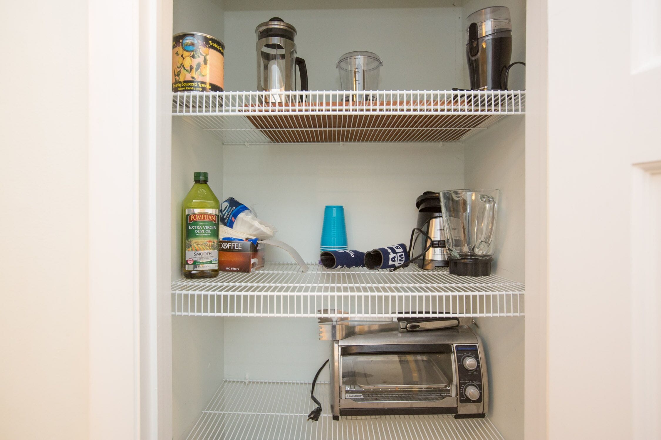 A kitchen with a coffee maker, blender, and toaster on the shelves.