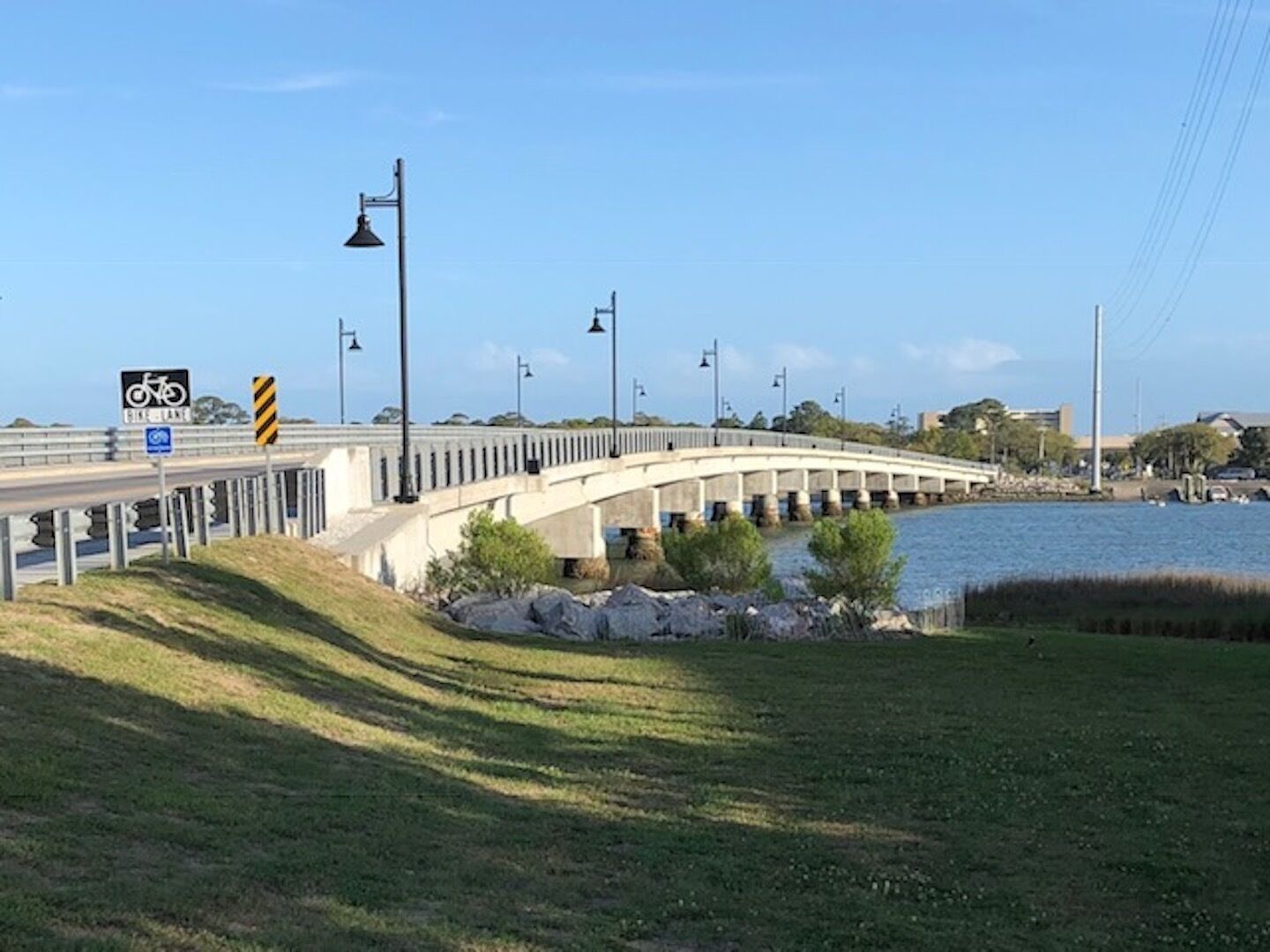 A bridge over a body of water with a bike lane sign and street lamps.