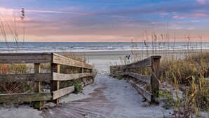 A wooden boardwalk leading to a beach with a clear view of the ocean.