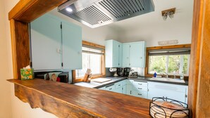 Een keuken met lichtblauwe kastjes, een houten aanrechtblad en een bord met de tekst 'SNACK SHACK'.