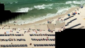 A beach with rows of sun loungers and umbrellas, a sandy shore, and the ocean in the background. - Beautiful Condo On The Gulf, Walking Distance to Pier Park (Panama City Beach)