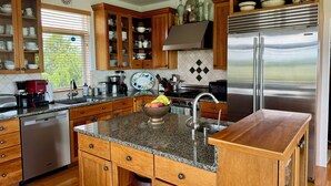 A kitchen with wooden cabinets, granite countertops, stainless steel appliances, and a view of the outdoors. - Steps to beach! Custom-built house with panoramic ocean views, wrap-around deck. (Guilford Center)