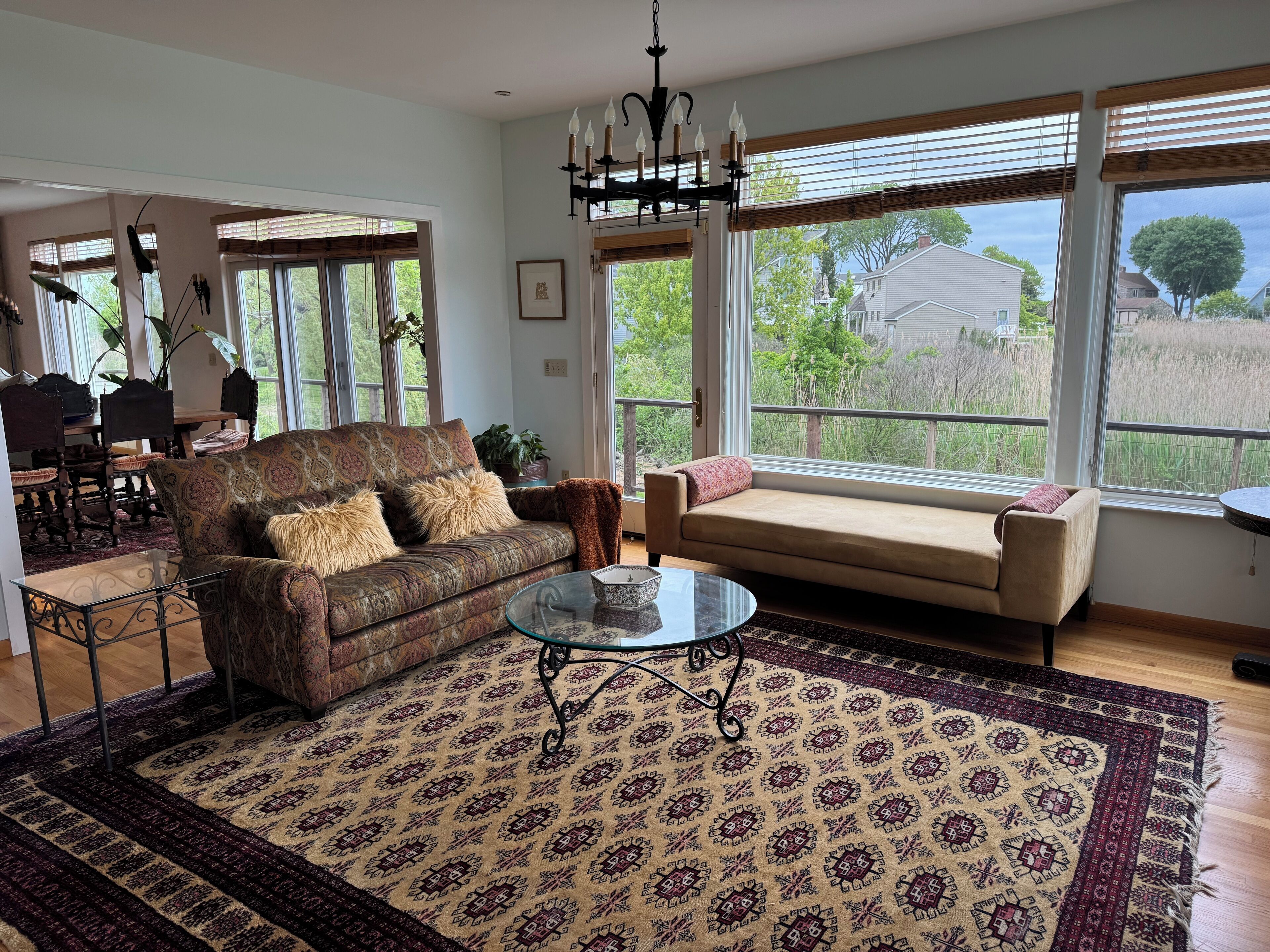 Ein Wohnzimmer mit einem gemusterten Sofa, einem Glastisch und Blick ins Freie.