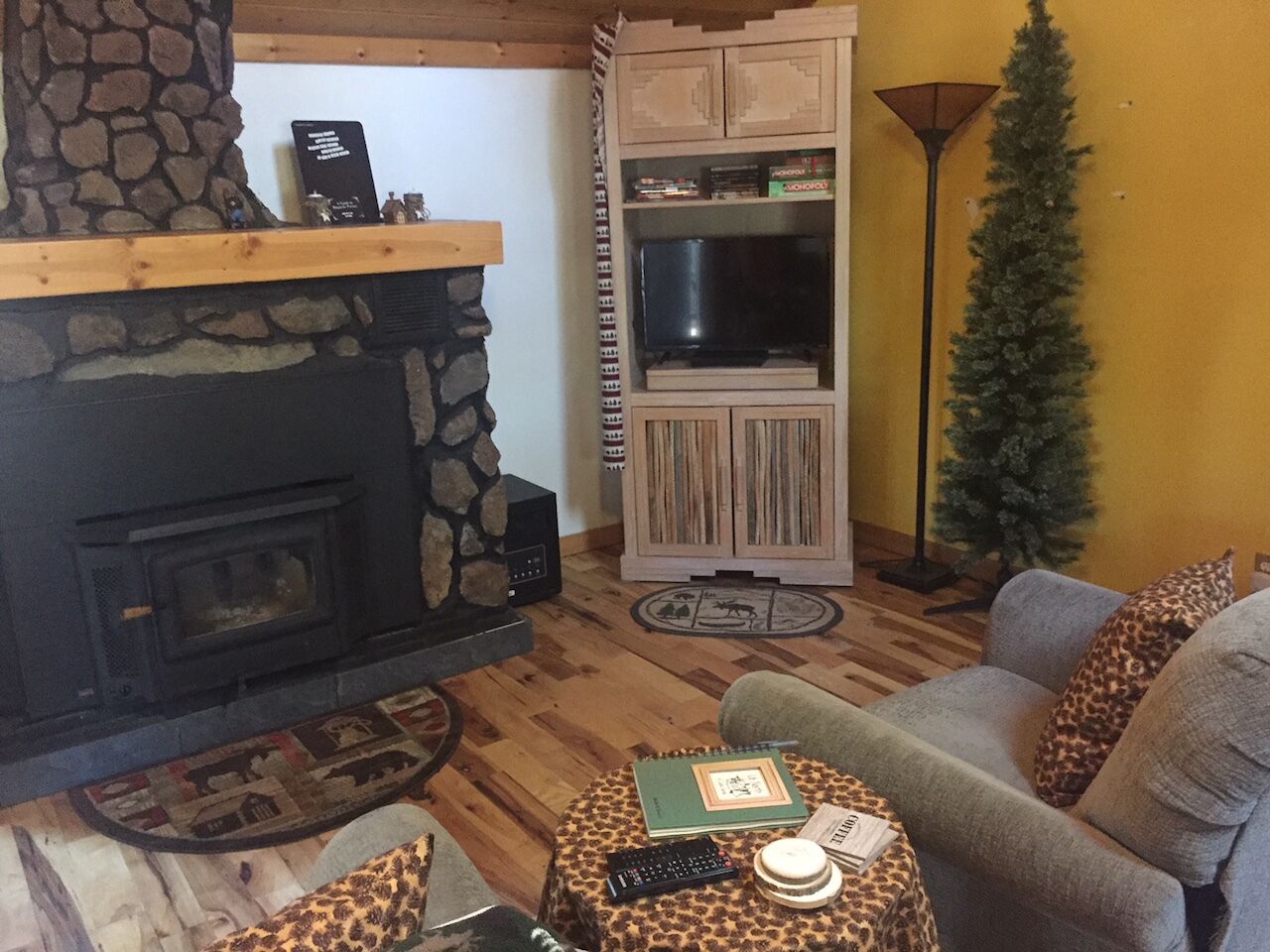 Una sala de estar acogedora con una chimenea de piedra, un televisor y un árbol de Navidad.