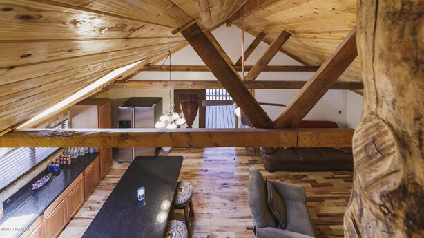 Una habitación rústica en el ático con vigas de madera a la vista, una mesa de comedor y un sofá.