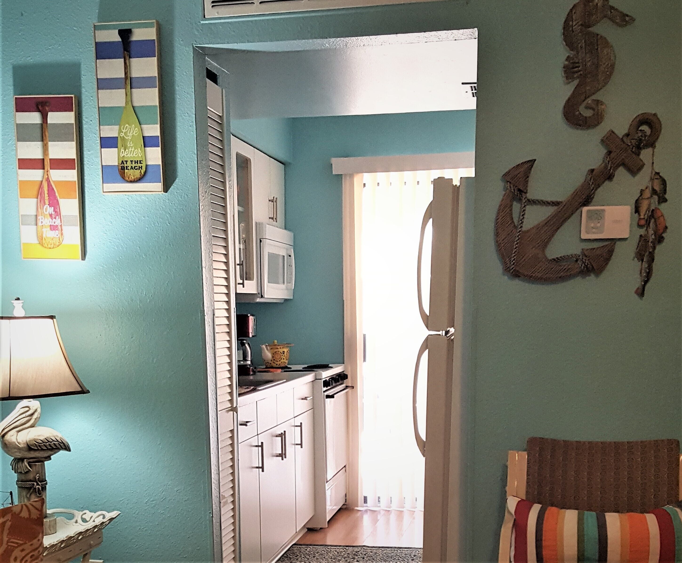 A kitchen with white cabinets, a microwave, and a stove. There is a door leading to another room.