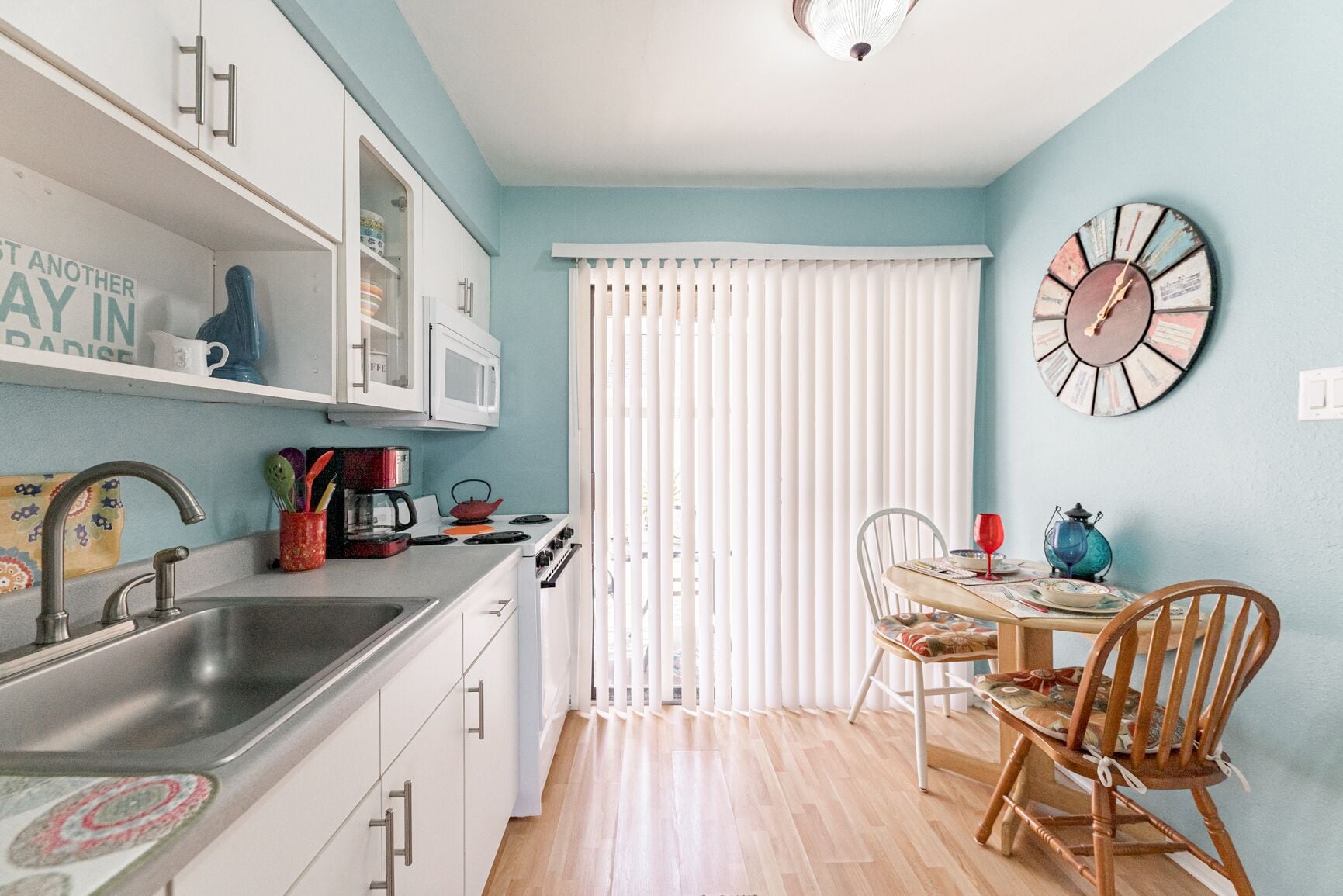 A compact kitchen with white cabinets, a sink, and a dining area with a table and chairs.