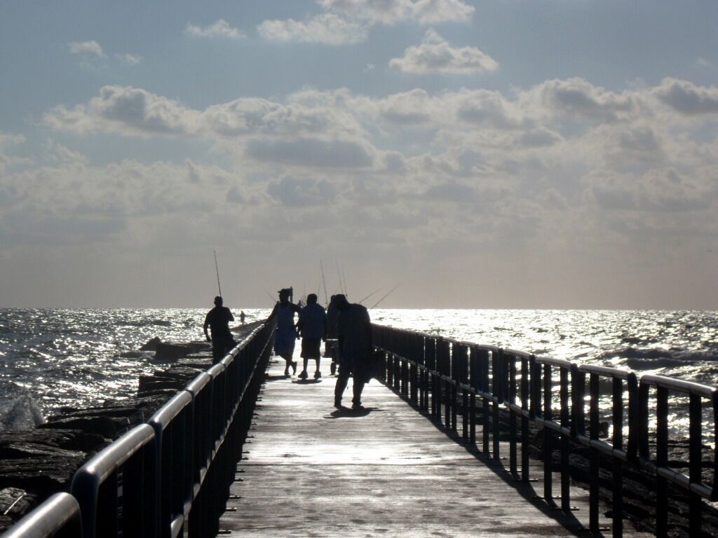 A pier extending into the sea with people fishing.