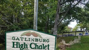 A sign for Gatlinburg High Chalet Condominiums, surrounded by rocks and greenery.