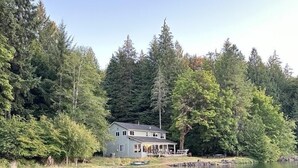 Una casa junto a un lago rodeada de un bosque frondoso.