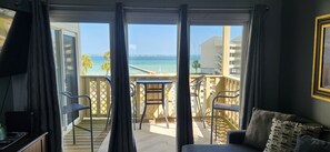 A balcony with a view of the sea, a table, and two chairs.