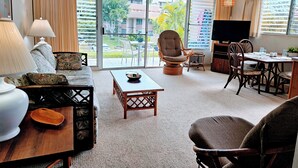 A spacious living room with a sofa, armchairs, a coffee table, and a dining area with chairs and a TV.