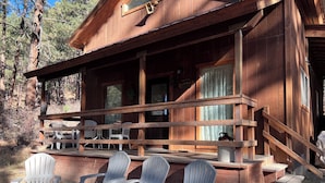 A wooden cabin with a porch, outdoor seating, and a staircase leading to the entrance.