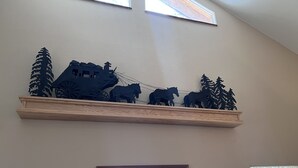 A wooden shelf with a black horse-drawn carriage and trees.