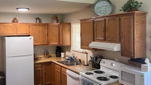 A kitchen with wooden cabinets, a white refrigerator, a stove, and a microwave.