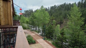 A wooden building with a balcony overlooking a forested area. - Spacious Luxury Downtown Riverfront Loft Condo.  License #6027 (Estes Park)