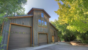 Un bâtiment rustique en bois, doté de deux portes de garage, d’un petit porche et d’une allée pavée.