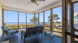A covered porch with wooden flooring, two rocking chairs, and a view of the beach and ocean. - BEACHFRONT! VIEWS! Pet Friendly! Fenced Yard! Winter Rates Available! (Panacea)