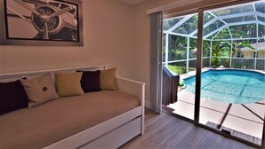 A bedroom with a bed, a painting, and a view of a swimming pool.