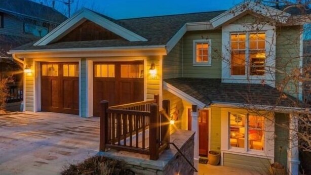 A two-story house with a front porch, a garage, and a small attached structure with a window.