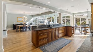 Un'ampia cucina con un'isola grande, mobili in legno e un'area pranzo con tavolo e sedie.