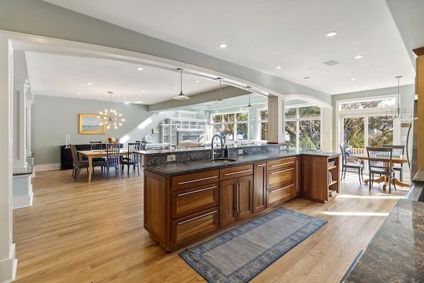 A spacious kitchen with a large island, wooden cabinets, and a dining area with a table and chairs.