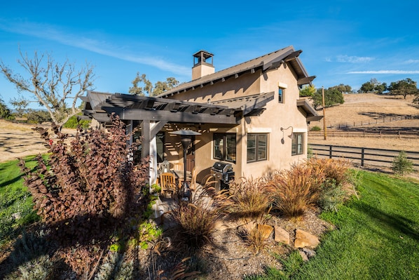 A house with a pergola, a chimney, and a well-maintained garden.