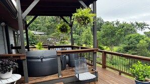 A wooden deck with a hot tub, a chair, and potted plants. - Peaceful and Serene w/ Hot Tub and View (Eureka Springs)