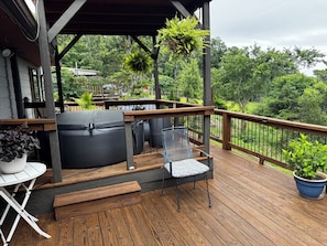 A wooden deck with a hot tub, a chair, and potted plants.