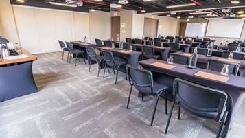 Une salle de conférence dotée de plusieurs tables et chaises, ainsi que de bouteilles d’eau et de plaques nominatives.