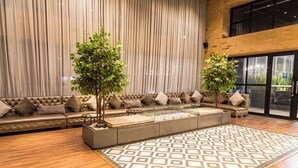 Un área de estar moderna con un sofá de cuero, dos plantas en macetas y un alfombra estampado.