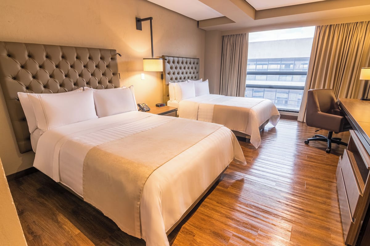 Una habitación de hotel con dos camas, un escritorio y una silla.
