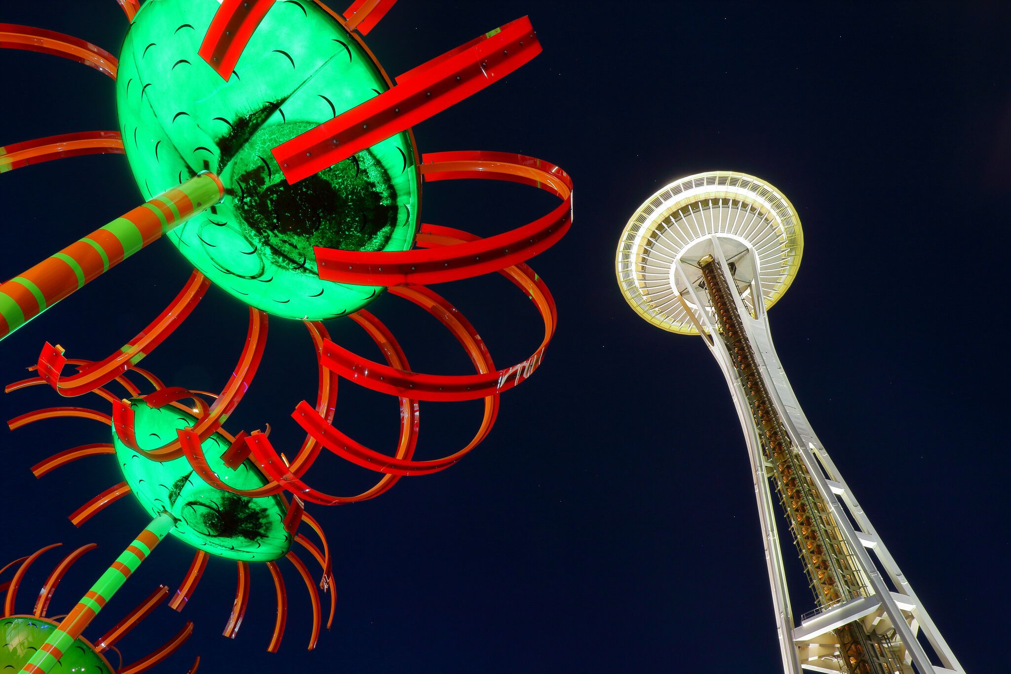 Uma roda gigante e uma estrutura de torre contra o céu noturno.
