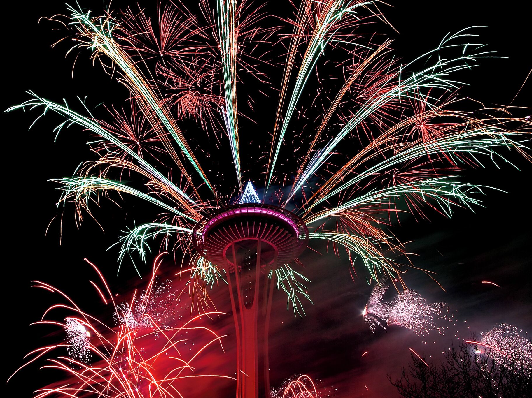Ein Turm mit einer kreisförmigen Aussichtsplattform und einer Spitze, umgeben von Feuerwerk.