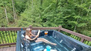 Un bain à remous sur une terrasse en bois, entouré d’arbres.