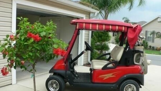 A red golf cart parked in front of a house with a garage.