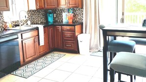 Een keuken met houten kastjes, een plafondventilator, een betegelde spatwand en een eethoek met een tafel en stoelen.