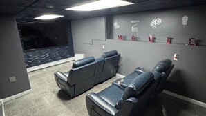 Een bioscoopzaal met luxe fauteuils, een popcornmachine en een muur met bioscoopthema.