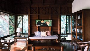 A wooden room with a bed, a bookshelf, and a painting on the wall. - Beach Front Home in Ballena Marine Natl Park (Uvita)
